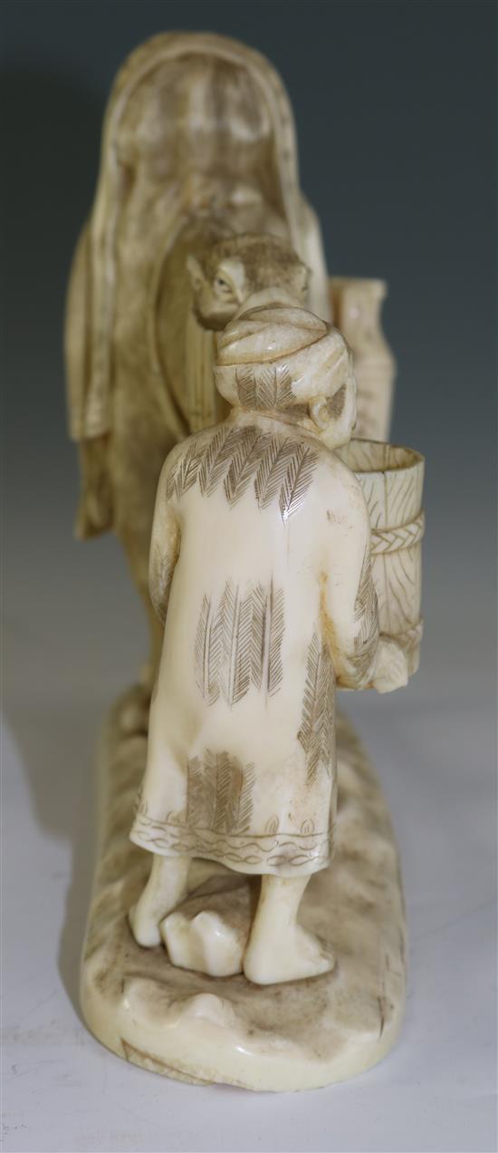 A Japanese sectional walrus ivory okimono of a Bactrian camel and a man, early 20th century, length 26cm